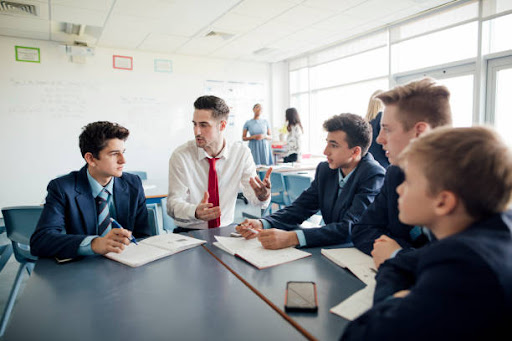 Young male student teacher talking to struggling students.