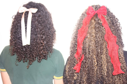 Two girls show off their curly hair and bows.
